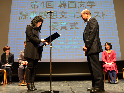 優秀賞の鈴木英雄さんの表彰状を読み上げる申京淑さん